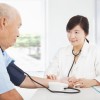 doctor measuring blood pressure of senior man at home