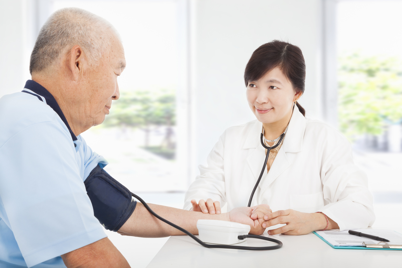 doctor measuring blood pressure of senior man at home