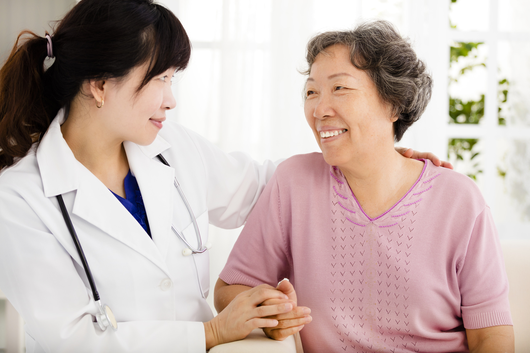 Nurse holding hand of senior woman in rest home